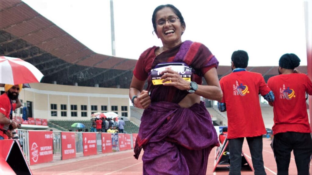 An Indian lady in Sari clothing running to finish a Marathon race.