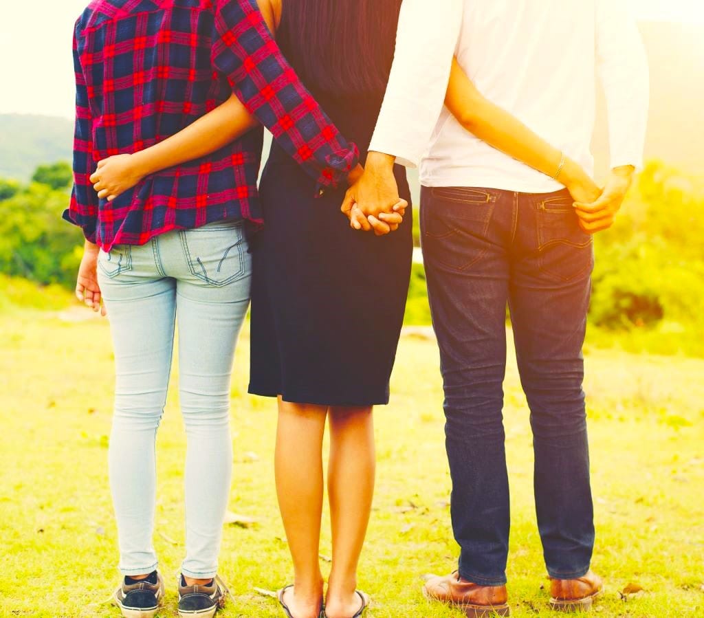 Three adults holding each other from the backside.